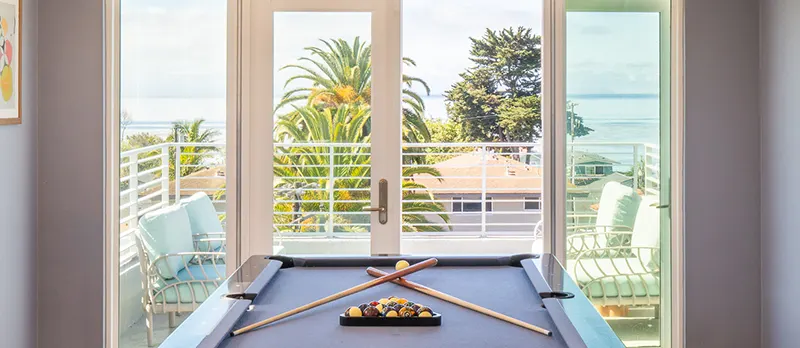 View of Campus Point Beach over the billiard table in the rooftop lounge at ICON Apartments